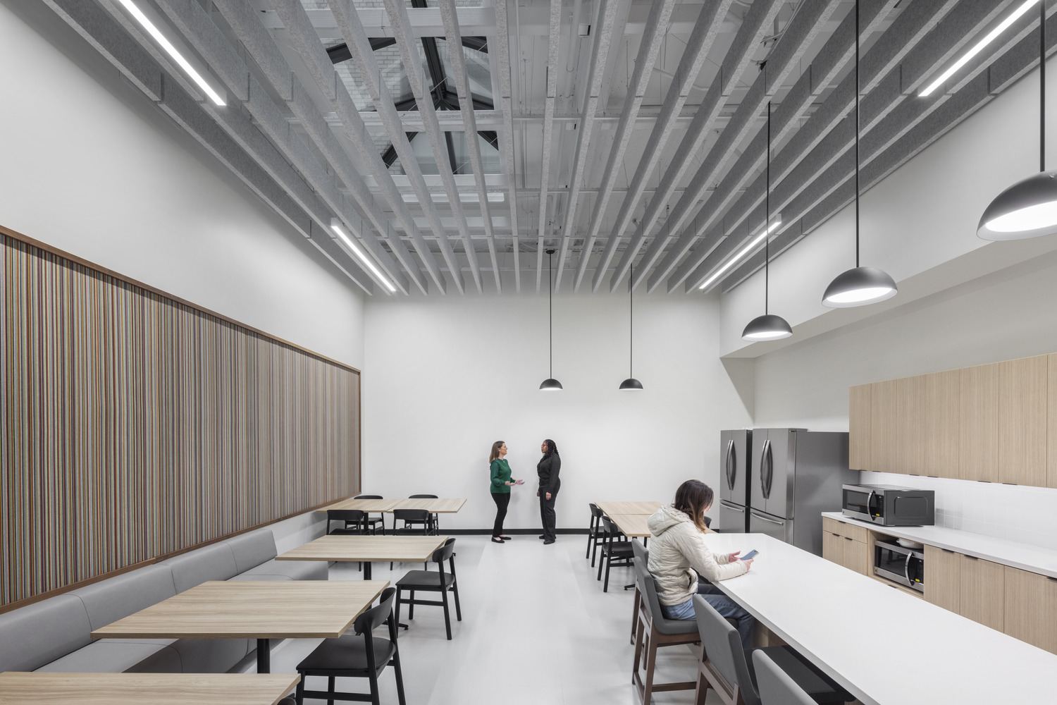 Renovated Jesse Unruh State Office Building break area with communal seating, kitchenette, and acoustic ceiling panels.