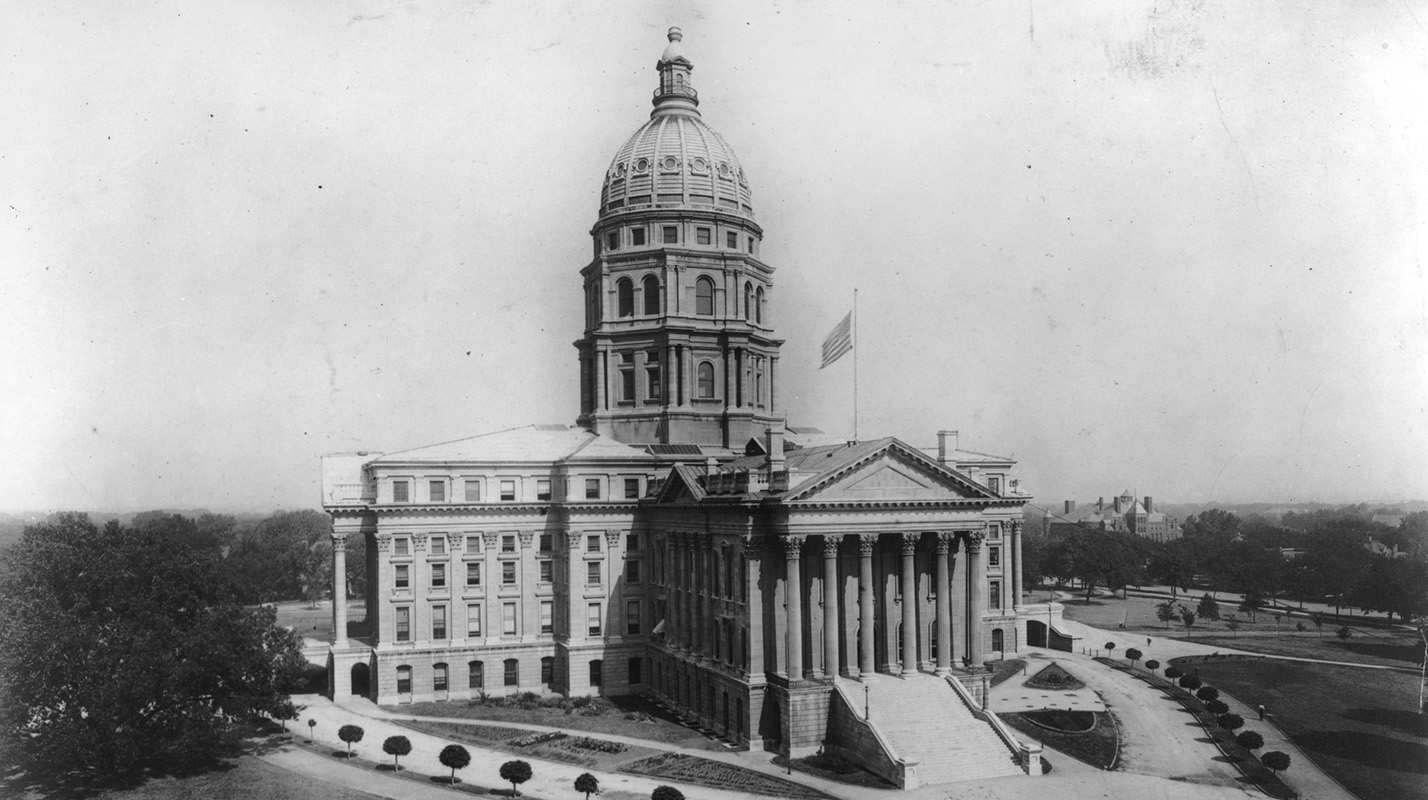 Black and white photo of the exterior of the Kansas State Capitol showing a large building with columns and a dome.