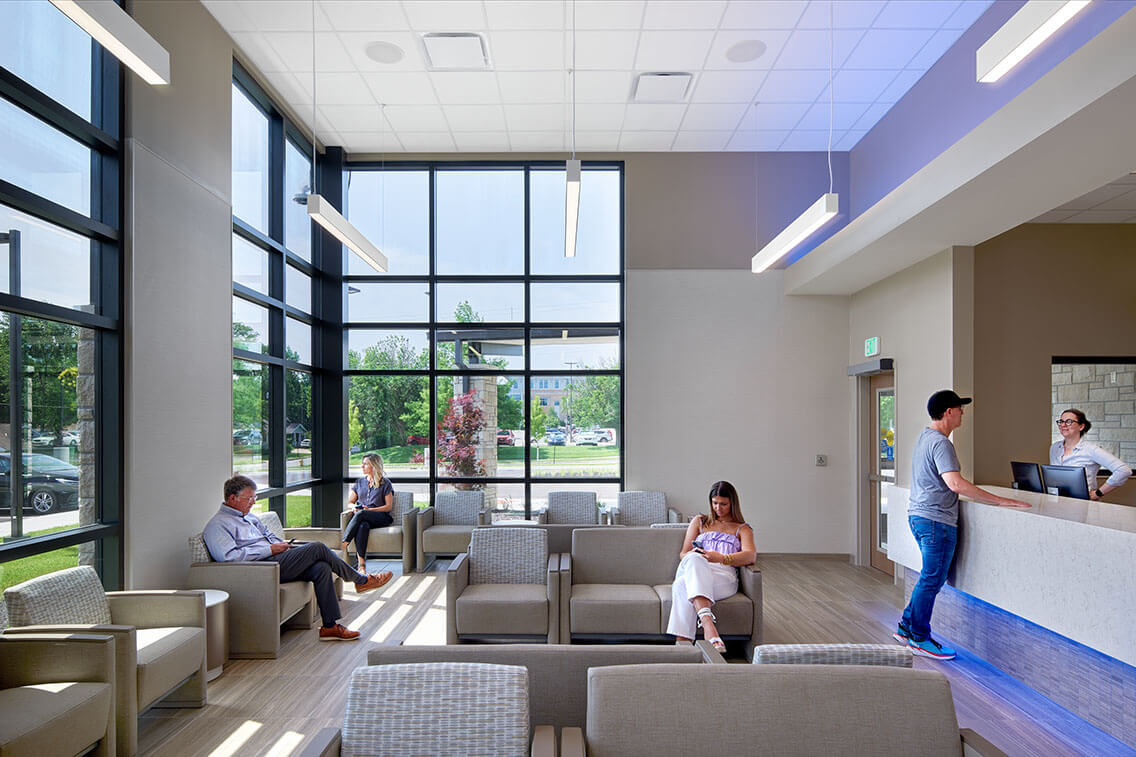 A close-up view of a waiting area inside the Douglas County Crisis Center. The area is designed with comfort in mind, featuring soft seating, low tables, and warm lighting. The space has a calm, neutral color scheme, with plants and artwork adding a touch of warmth and character.