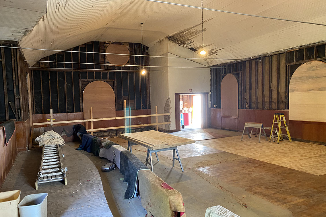 Interior photo of a church sanctuary during construction with the walls stripped down to the studs.