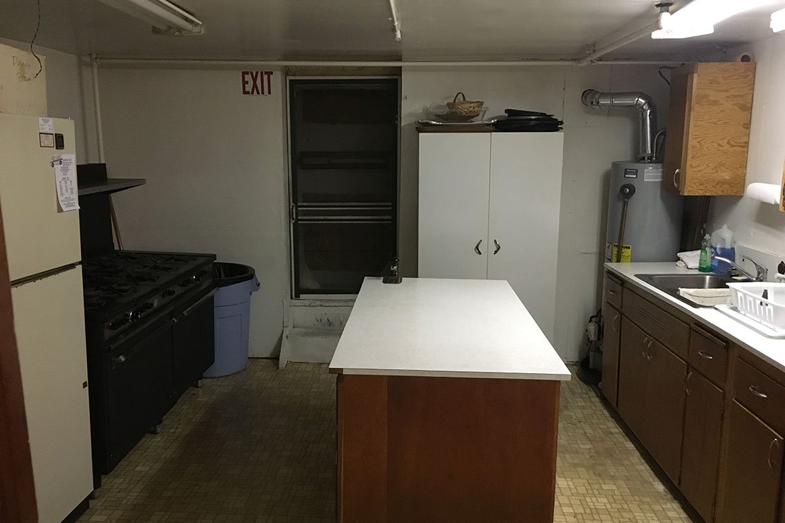 Photo of church kitchen with an island in the center and appliances to the left and right.