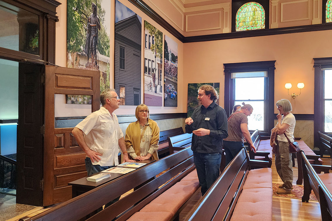 James Bibens discussing the preservation of the Historic Douglas County, Kansas, Courthouse's second floor courtroom, now the Douglas County Commission Chamber, with two people.
