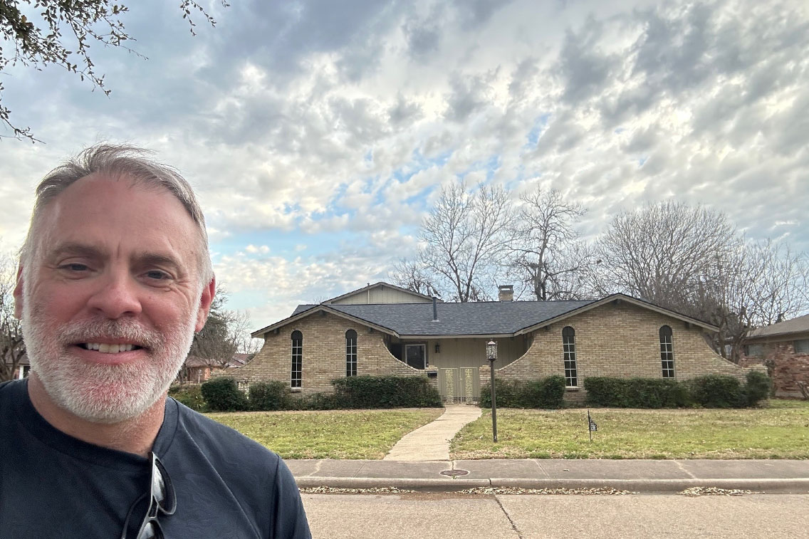 A selfie taken by a man in front of a historic house