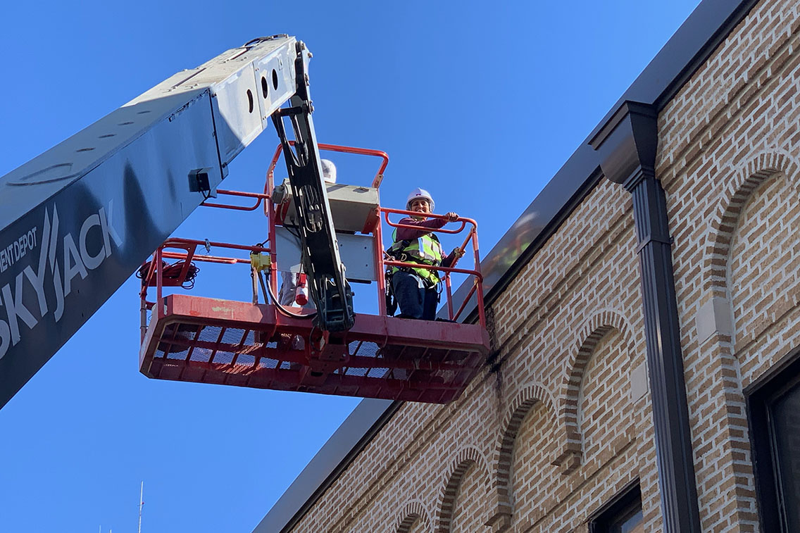 Urmila Srinivasan on a lift examining exterior brick masonry on a historic building