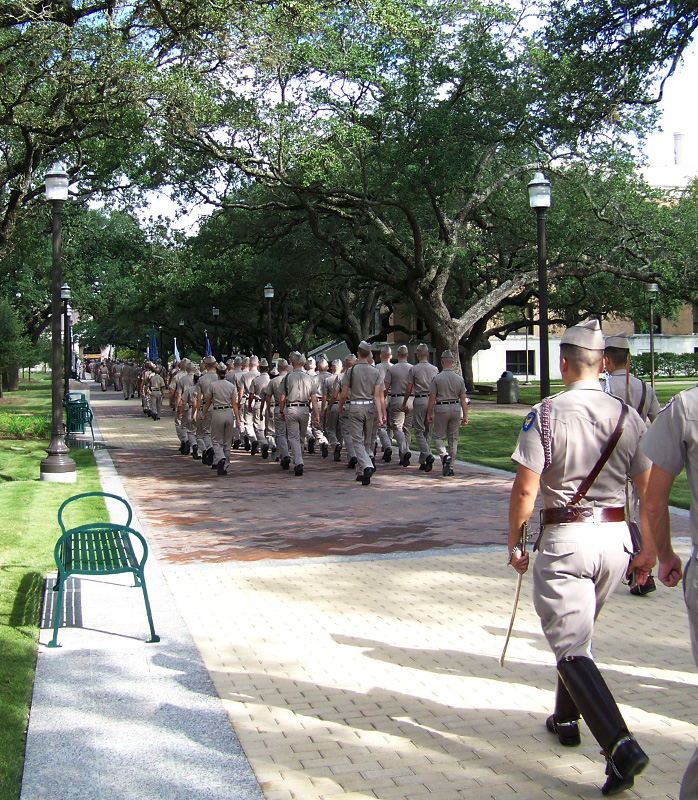 Corps of Cadets marching under live oaks on restored Military Walk, Texas A&M