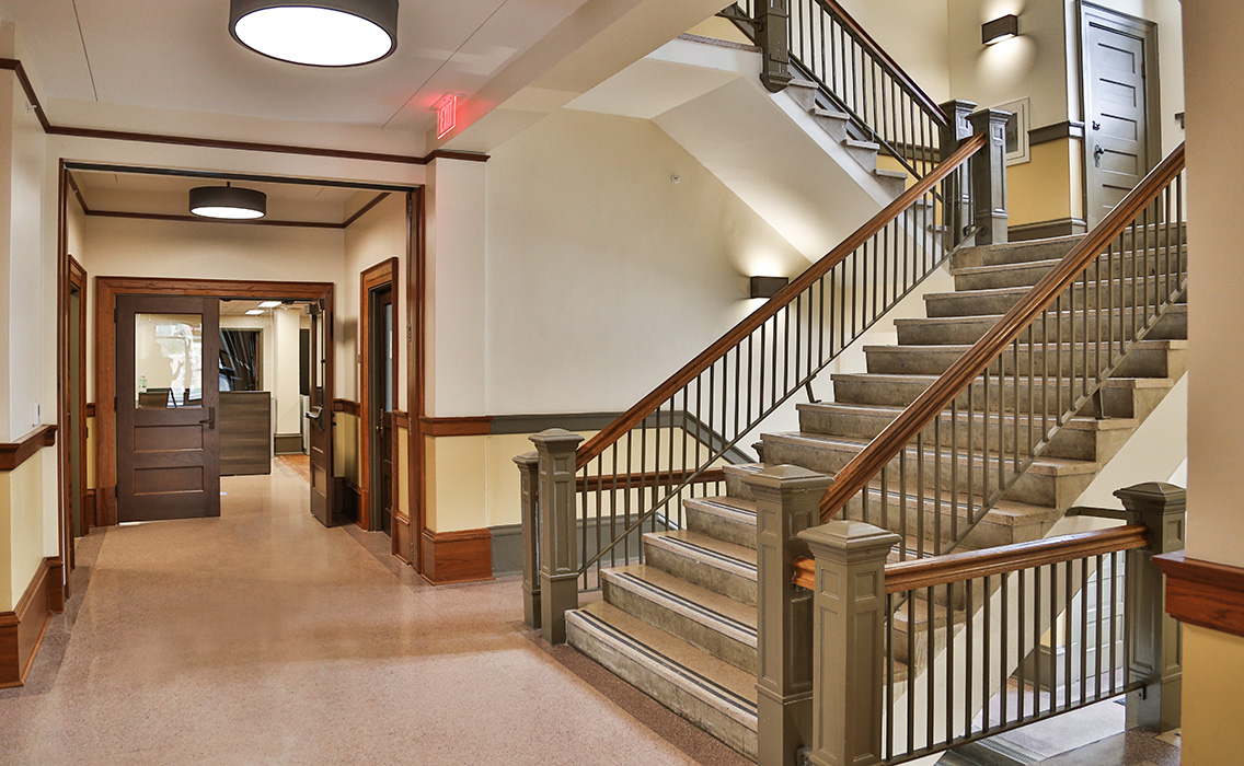 Restored central stair and corridor of Nagle Hall with original wood trim and plaster detailing.
